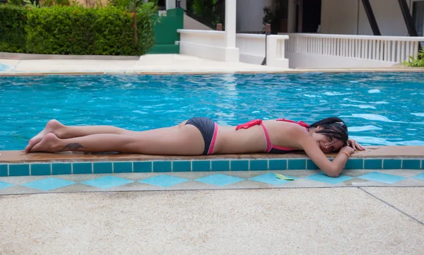Slender brunette lying by the pool — Stock Photo, Image