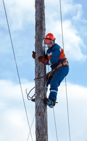 Eletricista sobe um poste de energia — Fotografia de Stock