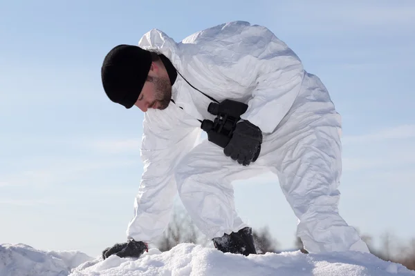 Zraněný voják v bílém maskování plížení přes sněhové hory a udělat — Stock fotografie