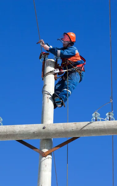 Elektrikář pracuje na vrcholu pylonu elektřiny — Stock fotografie