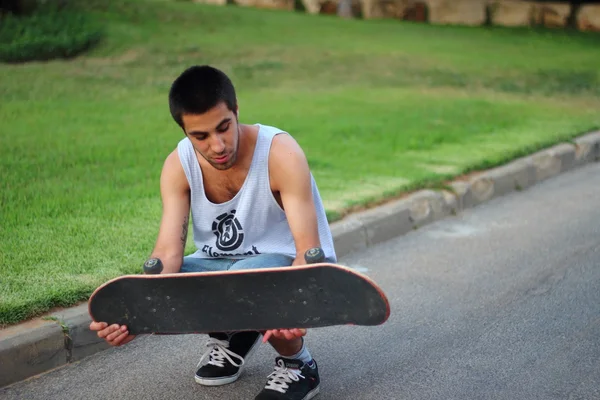Молодой человек держит скейт-борд — стоковое фото