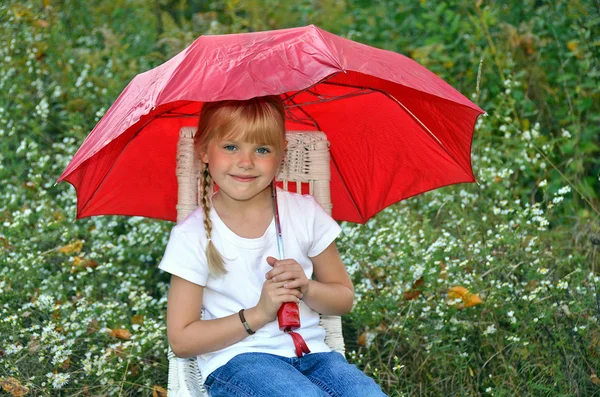 Kleines Mädchen unter einem roten Regenschirm — Stockfoto