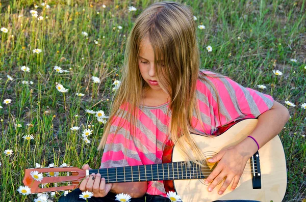 Mädchen mit Gitarre in wilden Gänseblümchen — Stockfoto