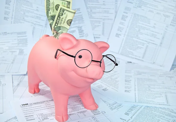 Piggy bank on income tax forms — Stock Photo, Image