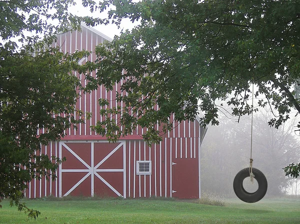 Tire swing by barn — Stock Photo, Image