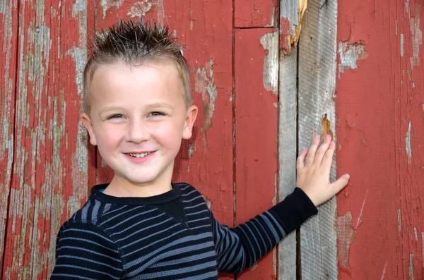 Uśmiechający się młody chłopak przez stodoła — Zdjęcie stockowe