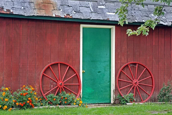 Wagon wheel and green door — Stock Photo, Image