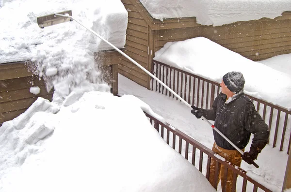 Человек убирает снег с крыши — стоковое фото