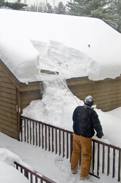 Homem removendo neve do telhado — Fotografia de Stock