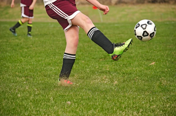 Jeune footballeur donnant un coup de pied à un ballon — Photo