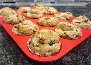 Kuru üzümlü kepekli kekleri kırmızı silikon pişirme tavasında kapat.