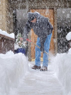 Caucasian man shoveling snow in a snowstorm 
