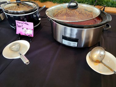 Crockpots on a tablecloth in a chili cook-off contest clipart