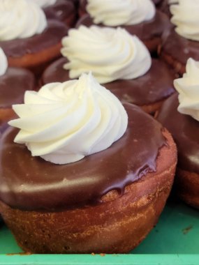 Yeşil bir pastanede, çikolatalı donutların üzerinde beyaz krema.