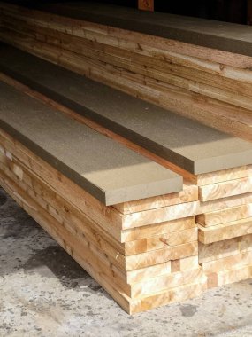 Kirli beton bir garajın zemininde çiğ tahtalar ve boyalı keresteler. 