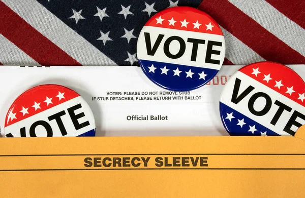 Election vote pins on a mail-in election ballot with an American flag