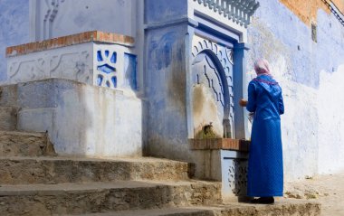 Muslim Woman by the Water Well in Streets of Chefchaouen, Morocco clipart