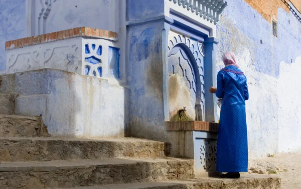 Muslimische Frau am Brunnen in den Straßen von Chefchaouen, Marokko — Stockfoto