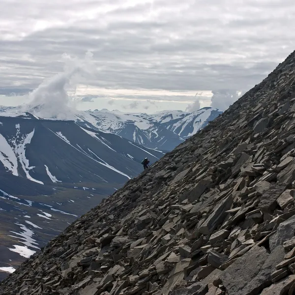 bir kişi tarafından gevşek taş kaplı sarp dağ tırmanışı.