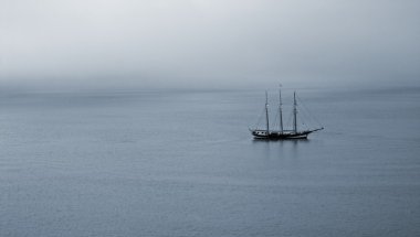 Sakin ve puslu bir deniz üzerinde yelkenli