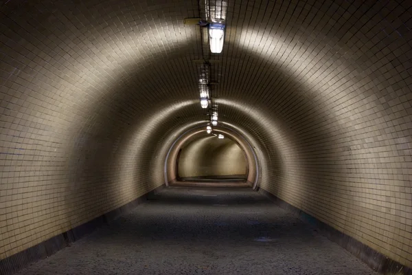 Perspektivvyn genom en mörk floodlighted tunnel — Stockfoto