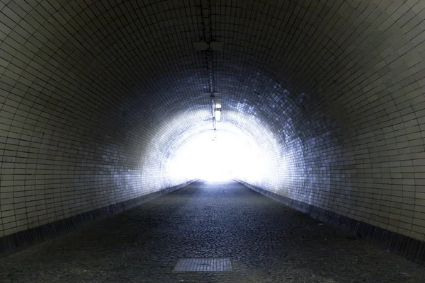 Vista através de um túnel escuro com a luz no final Fotos De Bancos De Imagens