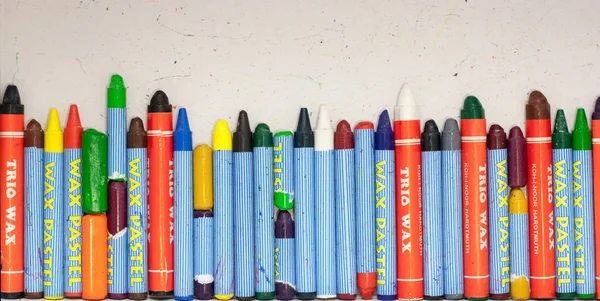Row of Used Wax Crayons on The Paper Background