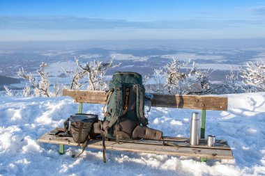 bir sırt çantası ve aksesuarları ile dağın üzerinde ahşap Bank