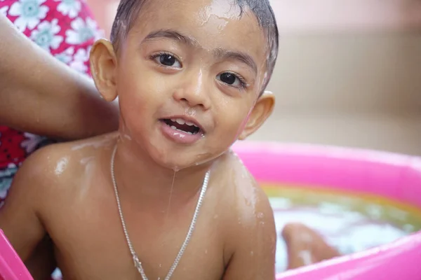 Um menino doce molhado durante o banho olhando para a câmera em uma piscina inflável — Fotografia de Stock