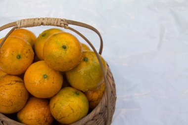 Taze olgun mandalina portakalları dokuma sepetinde birikir, su damlacıkları taze görünmesini sağlar. Portakallar tatlı ve lezzetlidir. Beyaz arka plana yerleştirilmiş, izole edilmiş, uzay. Chiang Mai Tayland.