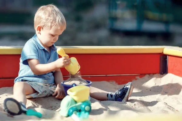 Menino Está Jogando Uma Caixa Areia Borda Vermelha Amarela Com — Fotografia de Stock