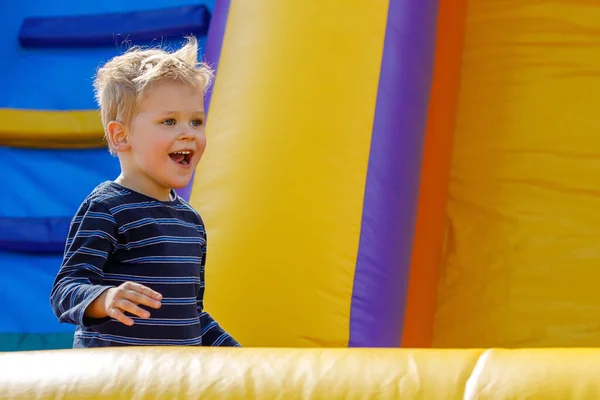 Smiling little boy playing outdoors on an inflatable bounce house.
