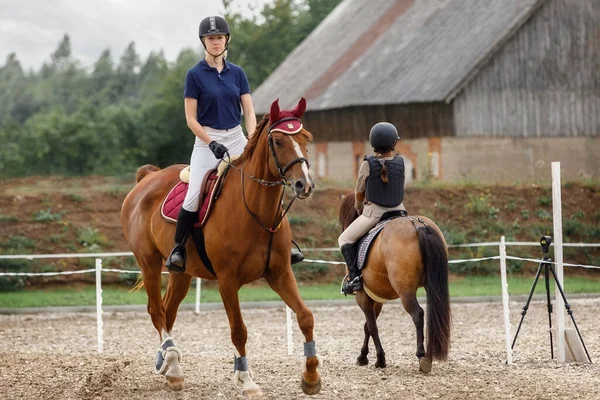 Equestrian sport -young girl rides on horse and little girl rides on pony in during training.
