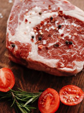 Çiğ pirzola bifteği, taze bitkiler ve kiraz domatesleri.