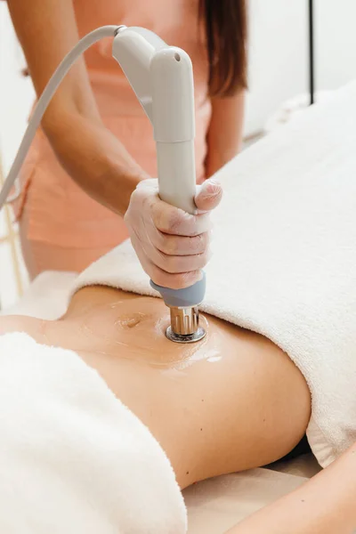 Concept of self care, getting rf-lifting treatment on female belly at cosmetology clinic