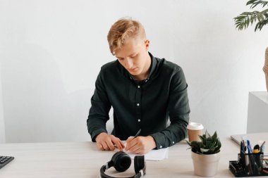 Gazetelerle çalışan ve kahve içen genç bir serbest yazar. Ofiste verimli günler.