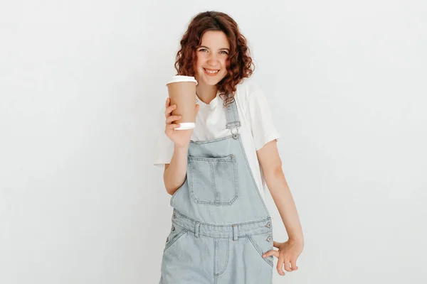 Young Woman Overalls Holding Hot Cup Coffee White Wall Free — Stock Photo, Image