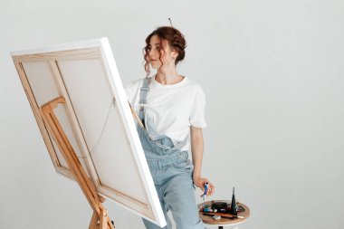 Stüdyosunda resim yapan kadın sanatçı. Kadın tuvale resim çiziyor. Stüdyosunda yağlı boya boya var.