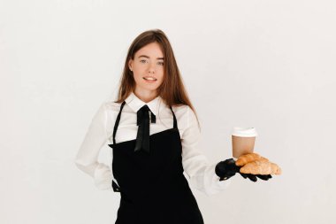 Genç garson müşterilerine taze kruvasan ve kahve ikram ediyor. Mükemmel kahvaltı konsepti