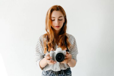 Kızıl saçlı kadın fotoğrafçı ışık stüdyosunda fotoğraf çekiyor. Hobi konsepti