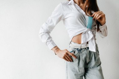 Portrait of model holding and presenting cream tube product. Adorable young woman with clean perfect skin isolated on white background. Beauty and skincare concept