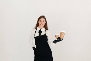 Dost canlısı garsonun portresi beyaz arka planda izole edilmiş iki paket kahve veriyor. Bir arkadaşa kahve.