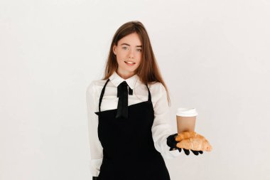 Genç garson müşterilerine taze kruvasan ve kahve ikram ediyor. Mükemmel kahvaltı konsepti