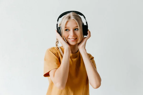 Wesoła Dziewczyna Słuchająca Muzyki Słuchawkach Żółtej Koszulce Białym Tle Studia — Zdjęcie stockowe