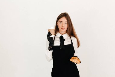 Genç garson müşterilerine taze kruvasan ve kahve ikram ediyor. Mükemmel kahvaltı konsepti