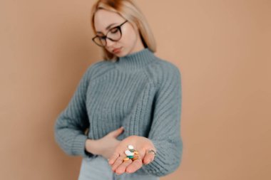 Genç bayan arka planda gözleri kapalı duruyor. Kızın sarı saçları ve büyük gözlükleri var.