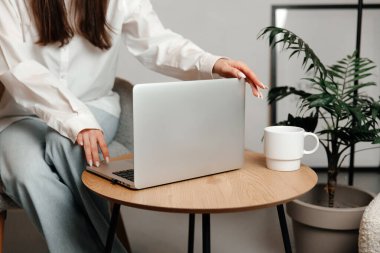 Laptop yakın plan çekilmiş. Bilgisayar ve beyaz bir bardak masanın üzerinde duruyor.