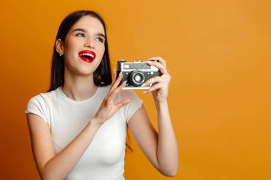 Genç bir kadın gündelik giyinmiş ve parlak makyaj yapıyor. Kız neşeli ve harika vakit geçiriyor.