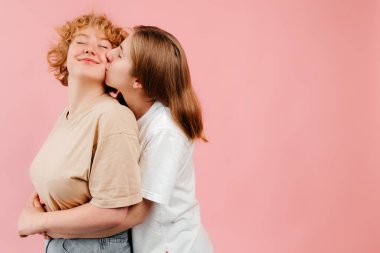Mutlu homoseksüel çift kucaklaşması fotoğrafı. Mutlu kızlar duygularını kutluyor, pembe arka planda birlikte eğleniyorlar. Romantik an konsepti