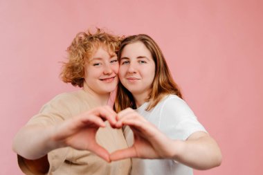Kızın elleri pembe arka planda izole edilmiş aşkın kalp şeklini simgeliyor. Romantik Sevgililer Günü konsepti